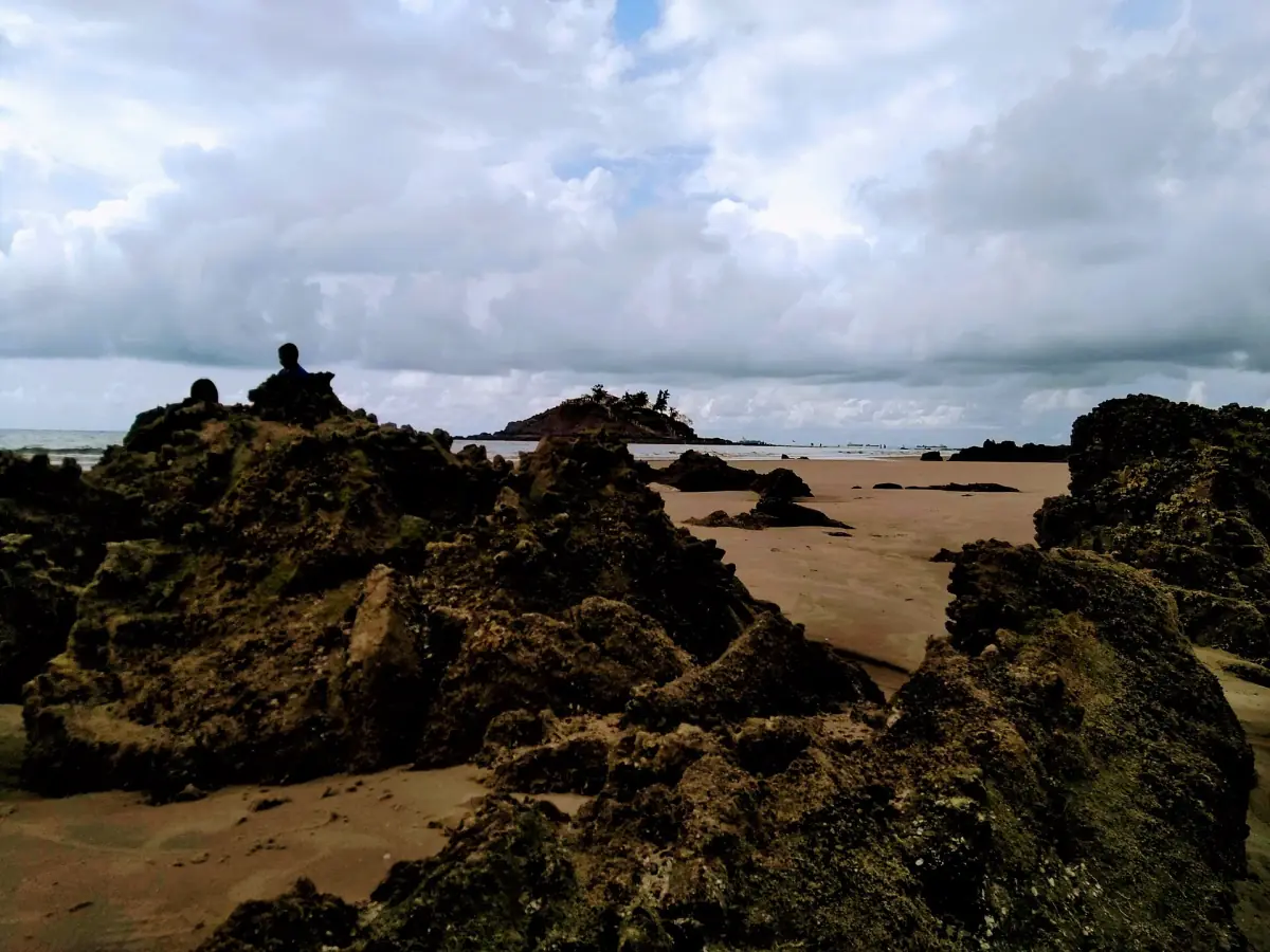 Back Beach with dark rocks, sand and cloudy sky at low tide