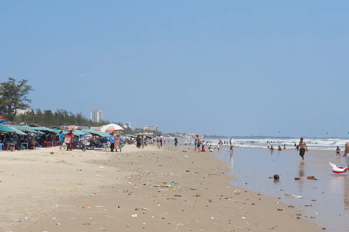 Wide sandy Back Beach with beach umbrellas and swimmers by the surf