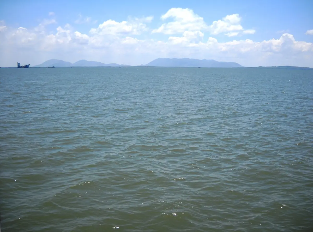 Calm blue sea with distant hills and white clouds in Ganh Rai Bay