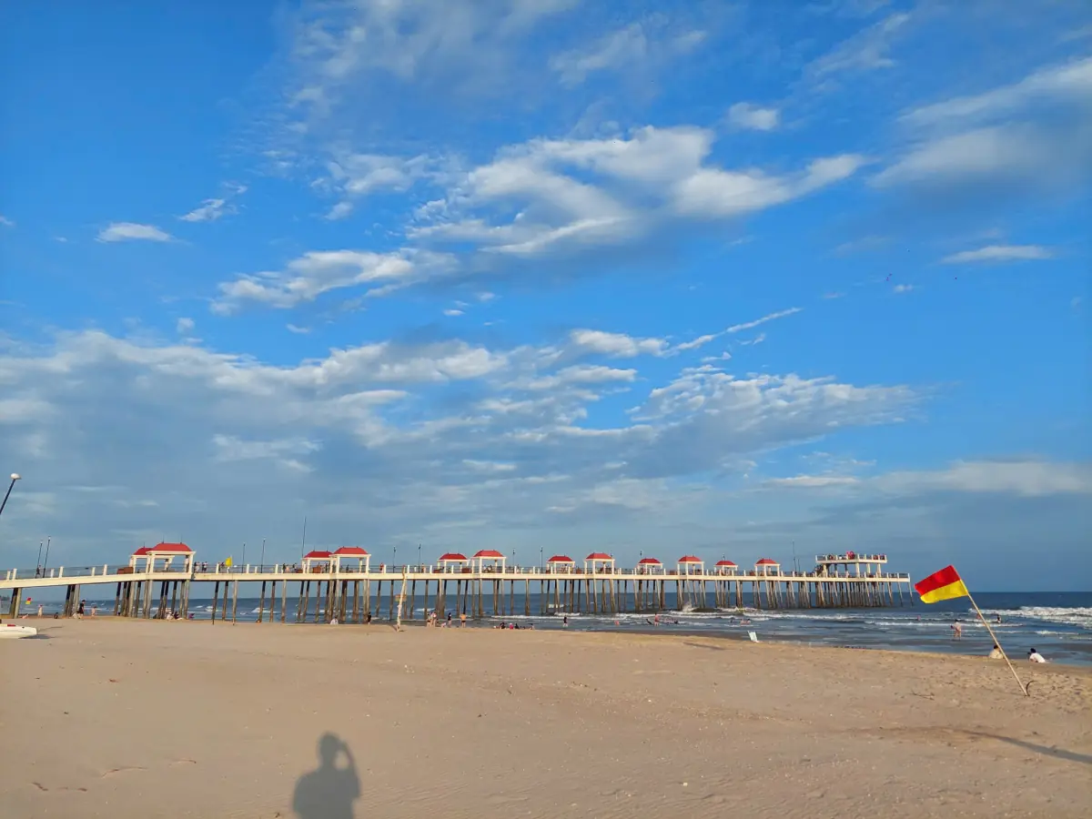 Calm sandy beach at Ho Tram with a long pier under blue sky
