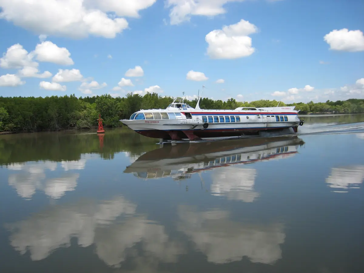 Hydrofoil speedboat on calm river with mangroves reflected in the water
