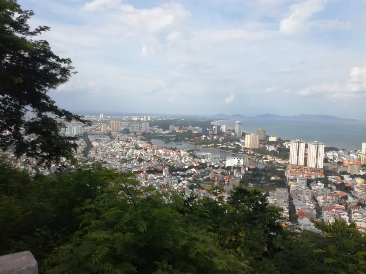 Hazy view of the city and coast from the lighthouse hill through trees