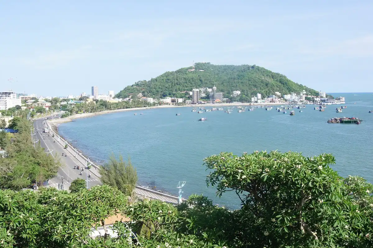Blue bay of Vung Tau with beach road and green headland