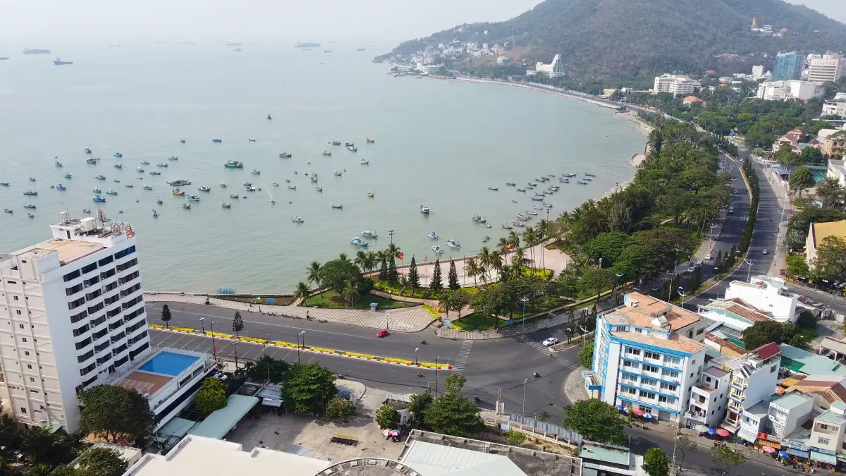 Curved coastline of Vung Tau with beach, boats and city seen from above